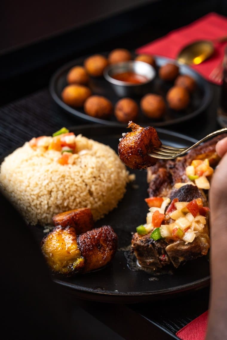 Table dressée : riz, brochettes de bœuf, allocos et beignets à partager